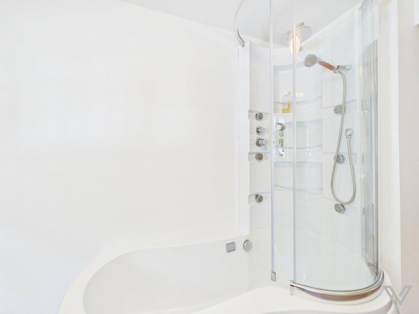 Badezimmer mit einer kombinierten Dusch- und Badewannenkabine in modernem Design.