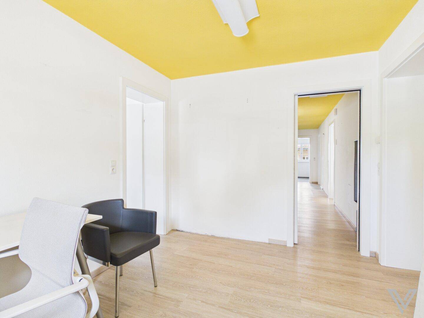 Heller Raum mit auffälliger gelber Decke und hellem Laminatboden, ideal als Büro.