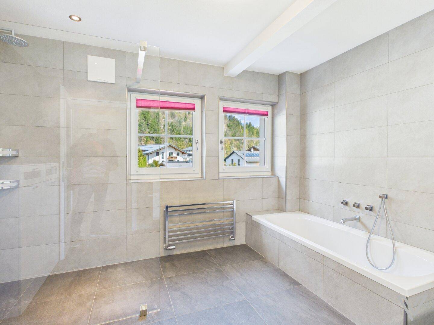 Modernes Badezimmer mit Badewanne, ebenerdiger Dusche und zwei Fenstern mit Ausblick.