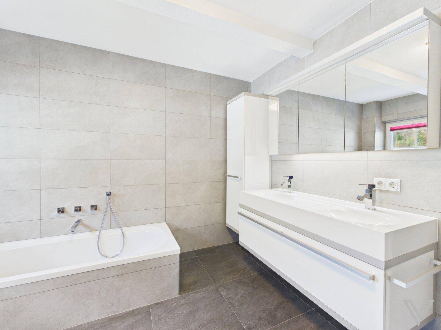 Modernes Badezimmer mit Doppelwaschbecken, Badewanne und großem Spiegelschrank.