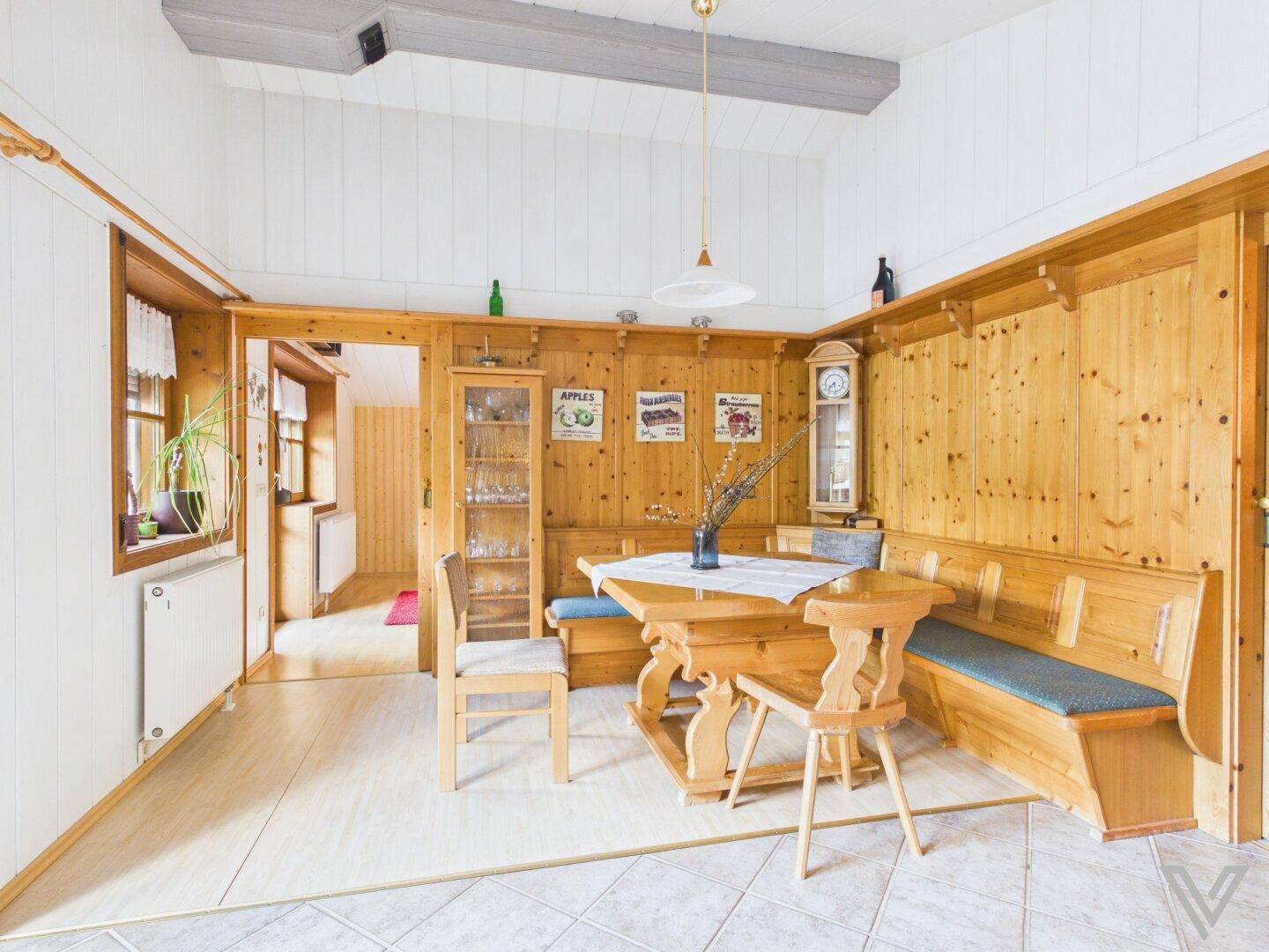 Traditioneller Essbereich mit Holztäfelung, Eckbank und einem großen Holztisch.