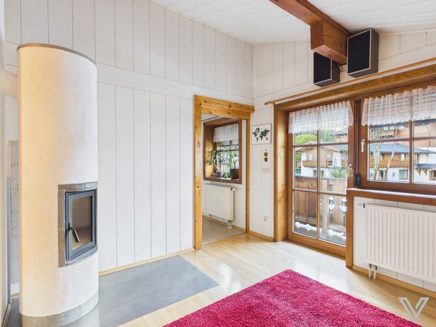 Wohnzimmer mit modernem Kaminofen, Holzwänden und Zugang zu einem Außenbereich.