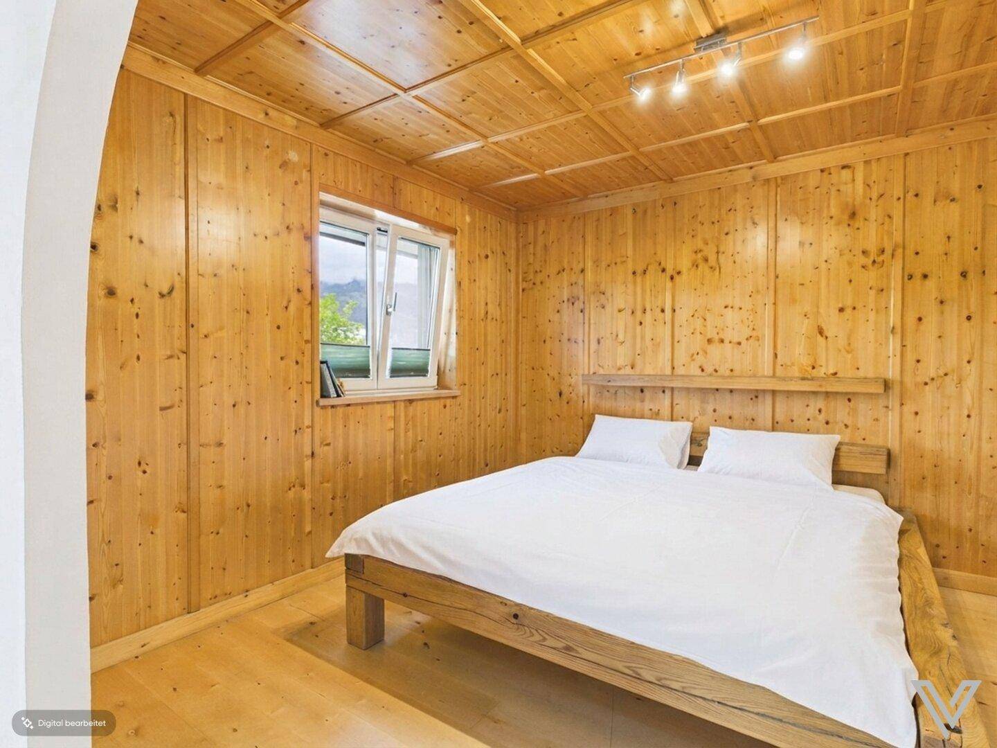 Schlafzimmer im alpinen Stil mit Holzvertäfelung, Holzbett und Parkettboden.