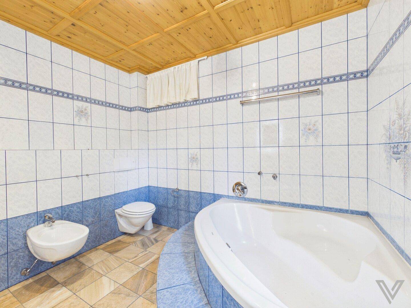 Badezimmer mit blauen und weißen Fliesen, Badewanne, WC und Bidet.