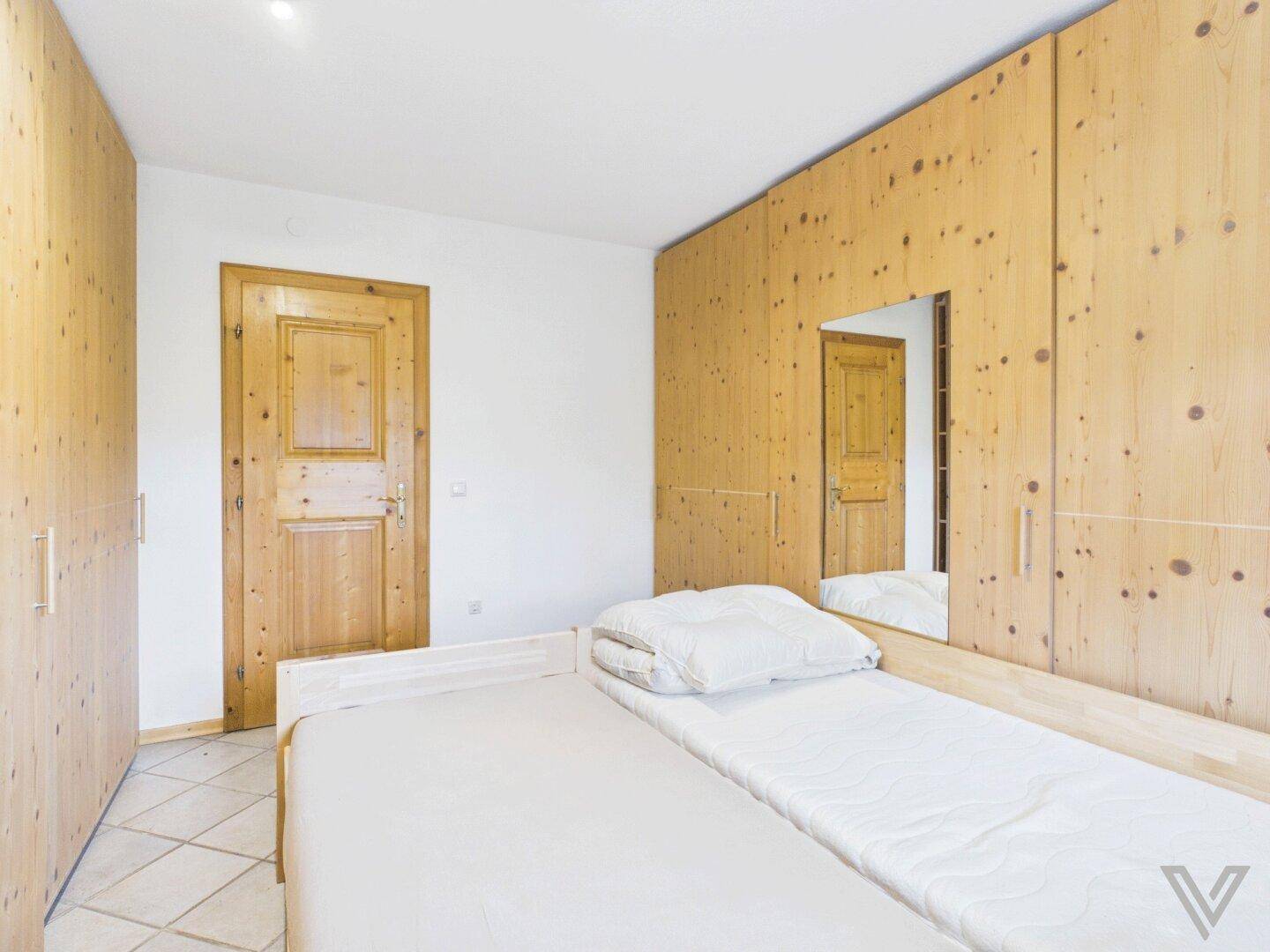 Schlafzimmer mit Holzschränken, Einzelbetten und Holztür.