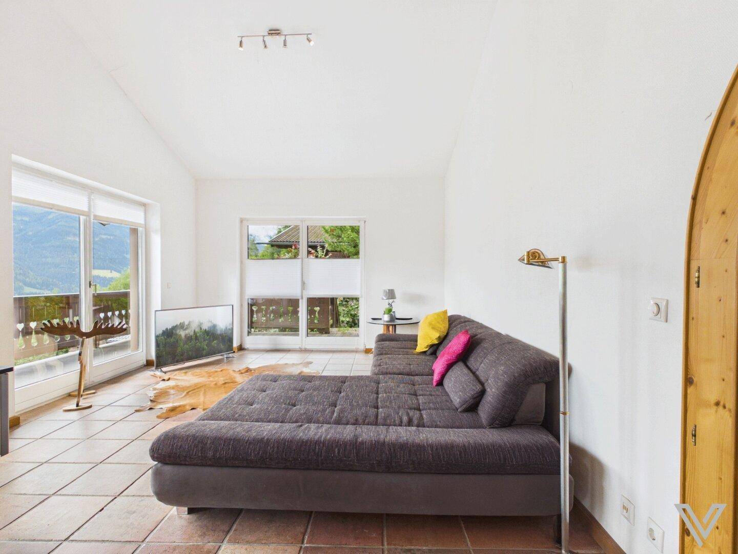 Geräumiger Wohnbereich mit bequemer Couch, Terrakottafliesen und Balkonzugang.