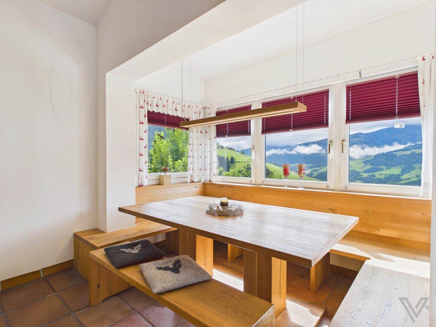 Essbereich mit Holzbänken, großem Tisch und Panoramablick auf die Berge.
