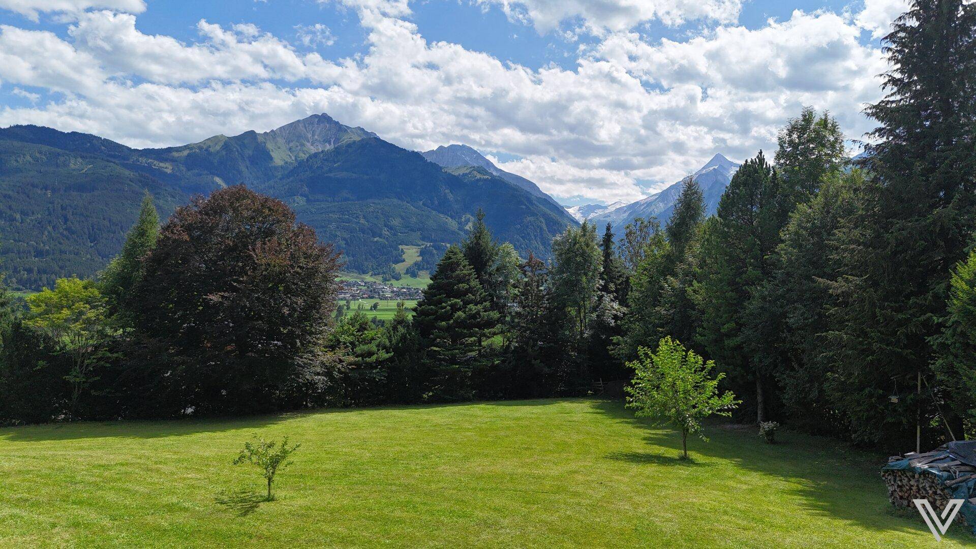 Panoramablick vom Garten über die weite Landschaft mit Bergen und einem Dorf im Tal.