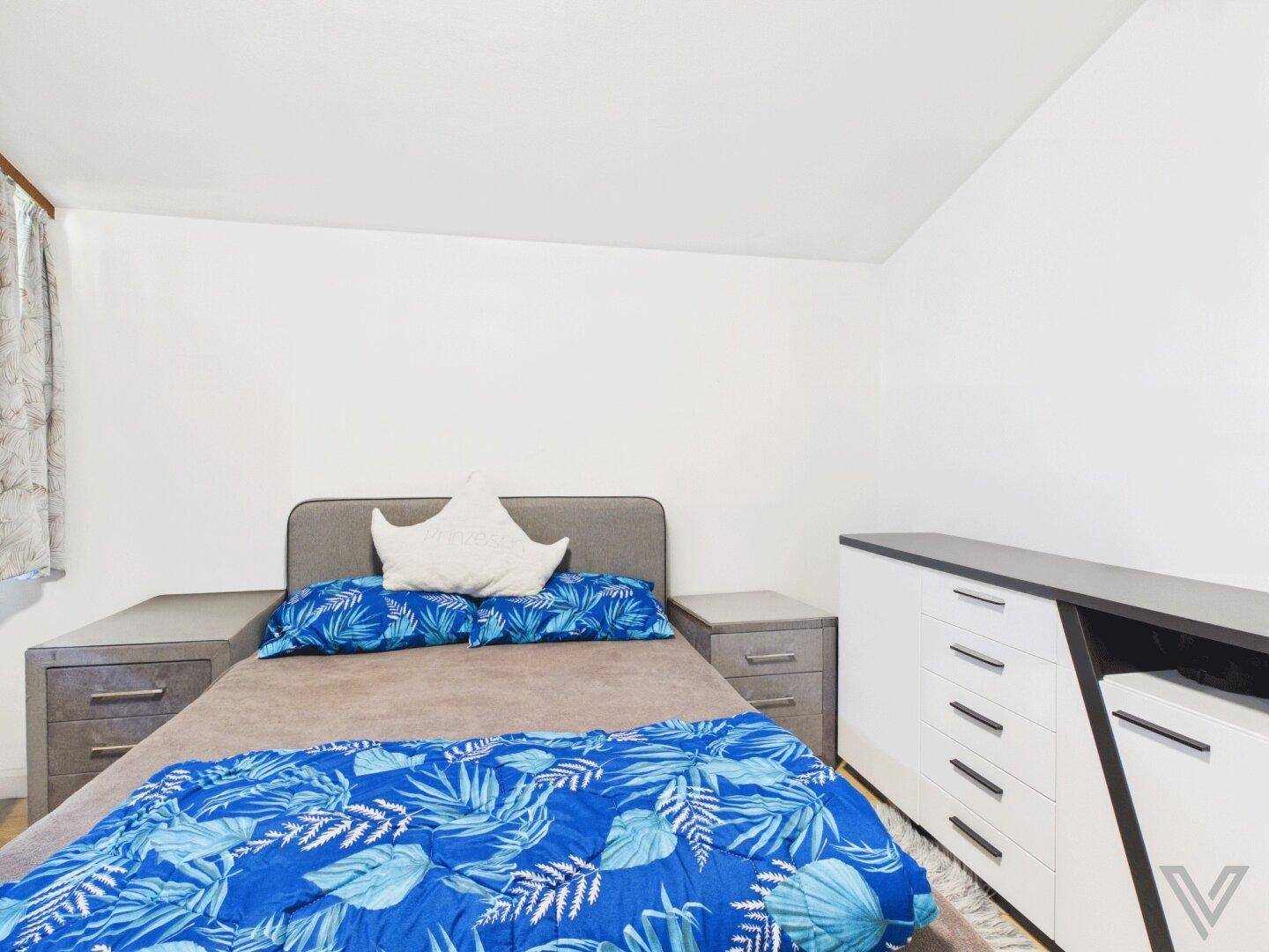 Modern eingerichtetes Schlafzimmer mit Doppelbett, Nachttischen und Kommode.
