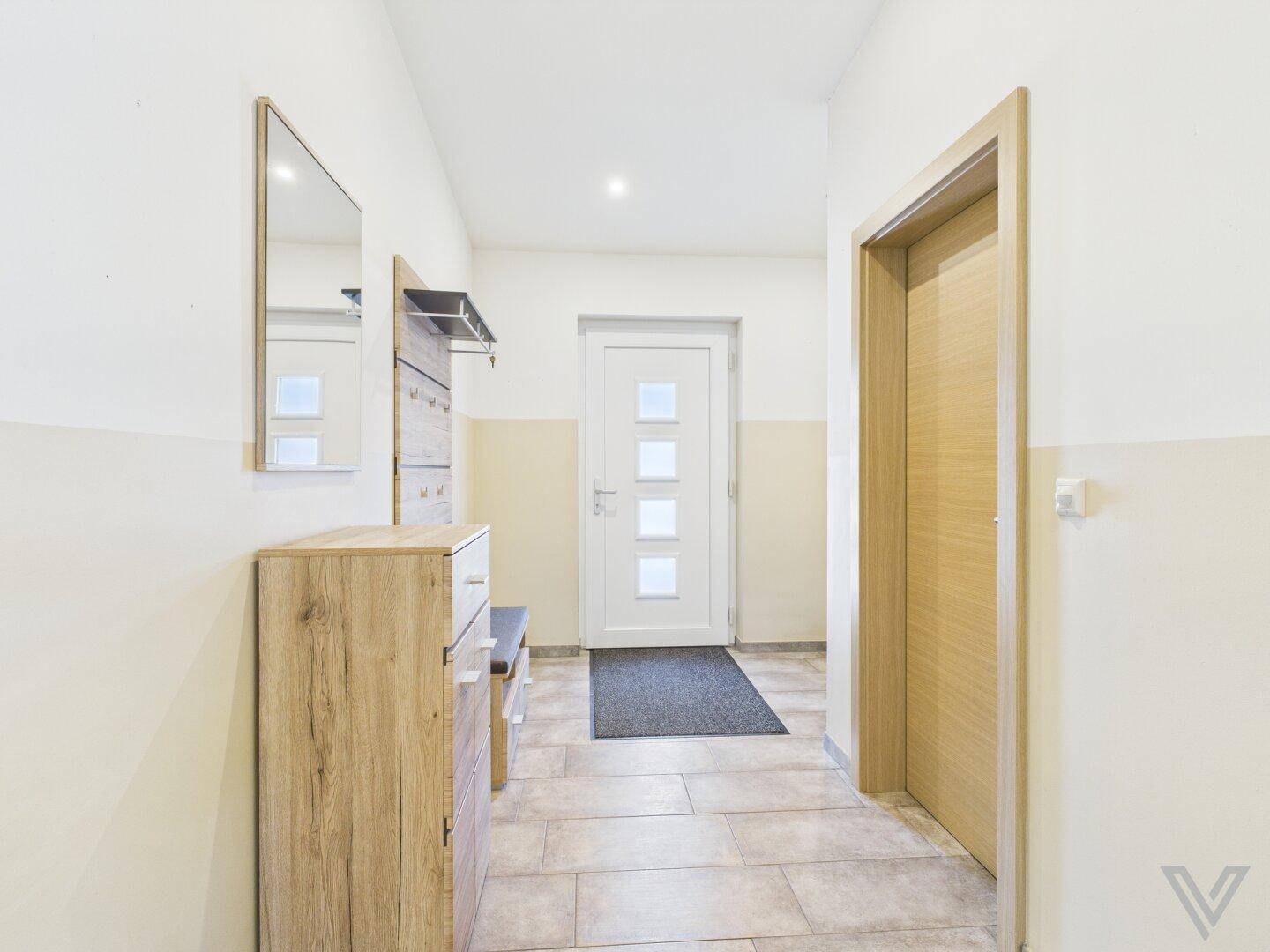 Eingangsbereich mit Garderobe, Spiegel und heller Eingangstür.