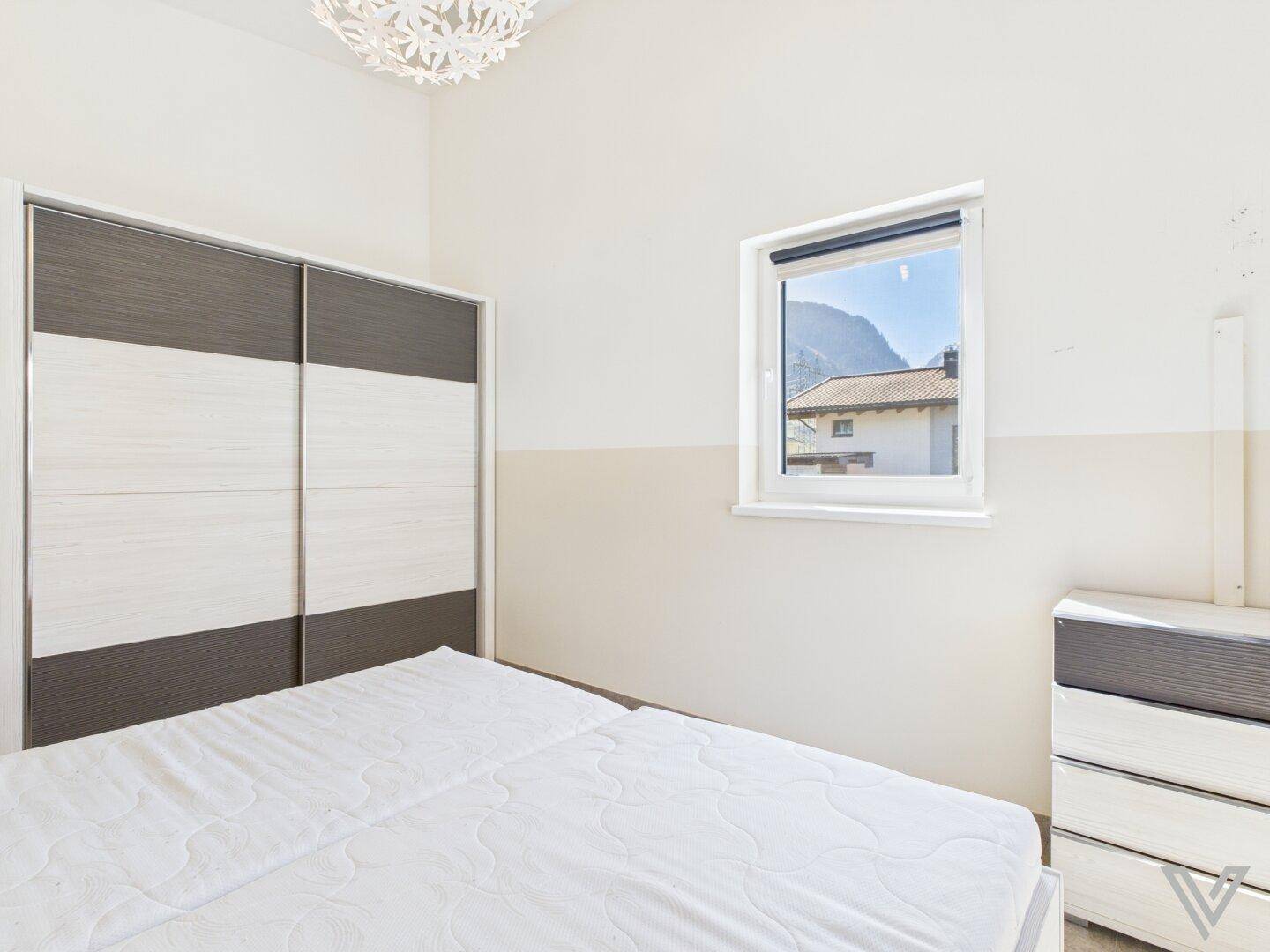 Schlafzimmer mit Doppelbett, Schiebetürenschrank und Blick auf die Berge.