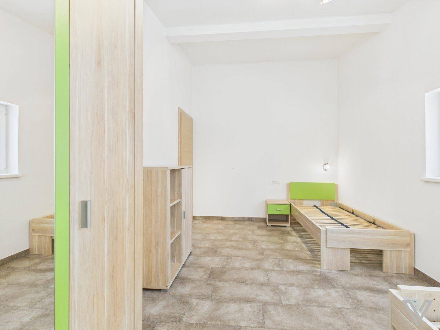 Kinderzimmer oder Gästezimmer mit Einzelbett, Schrank und hellem Holzmobiliar.