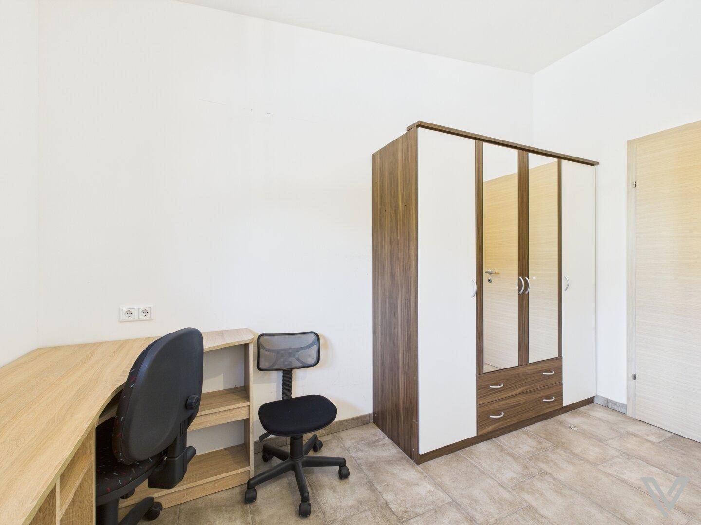 Arbeitszimmer mit Schreibtisch und großem Spiegelschrank, ideal für Home-Office.