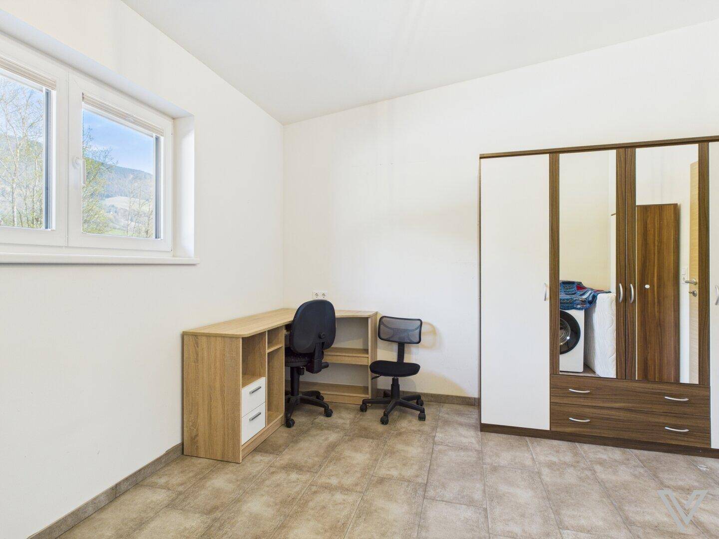 Arbeitszimmer mit Schreibtisch, Bürostühlen und großem Spiegelschrank.