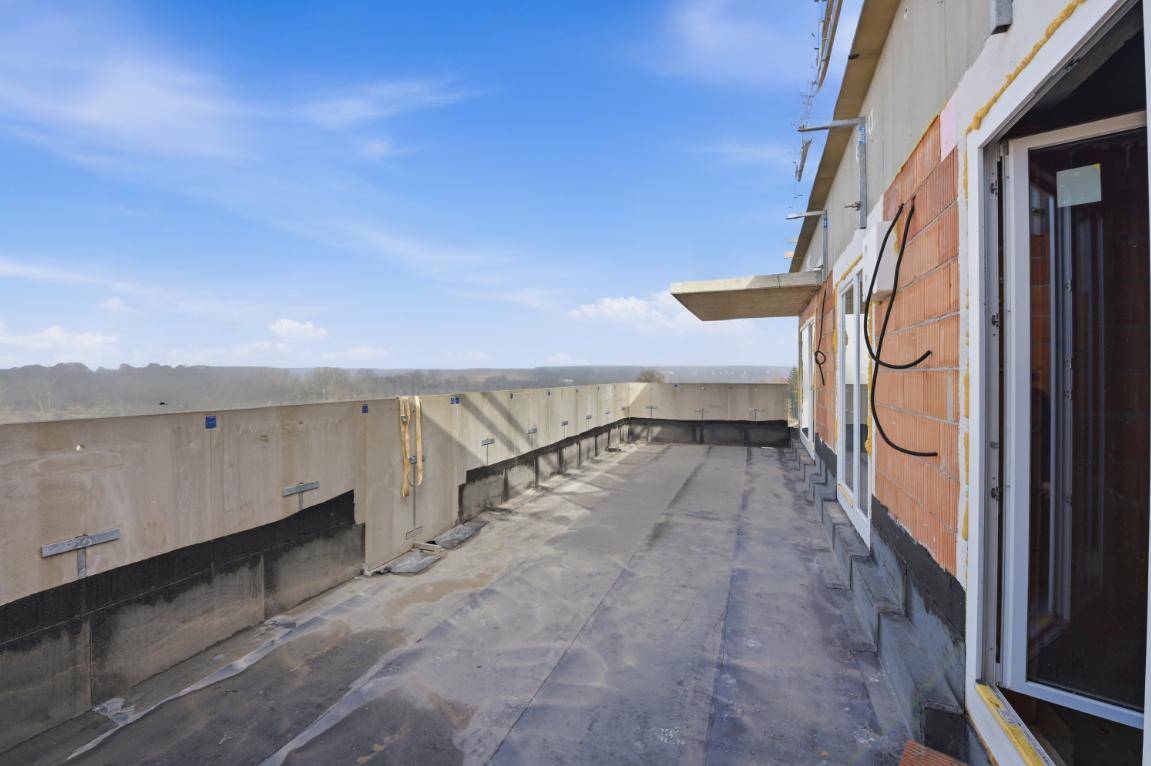 Große, unfertige Dachterrasse mit weitem Blick in die Landschaft und blauen Himmel.