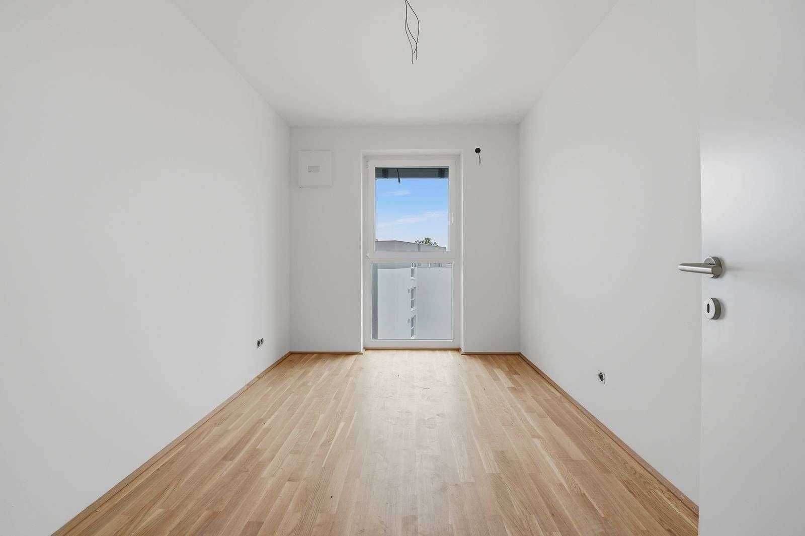 Unmöbliertes Zimmer mit Holzboden und Fenster, ideal als Gäste- oder Arbeitszimmer.
