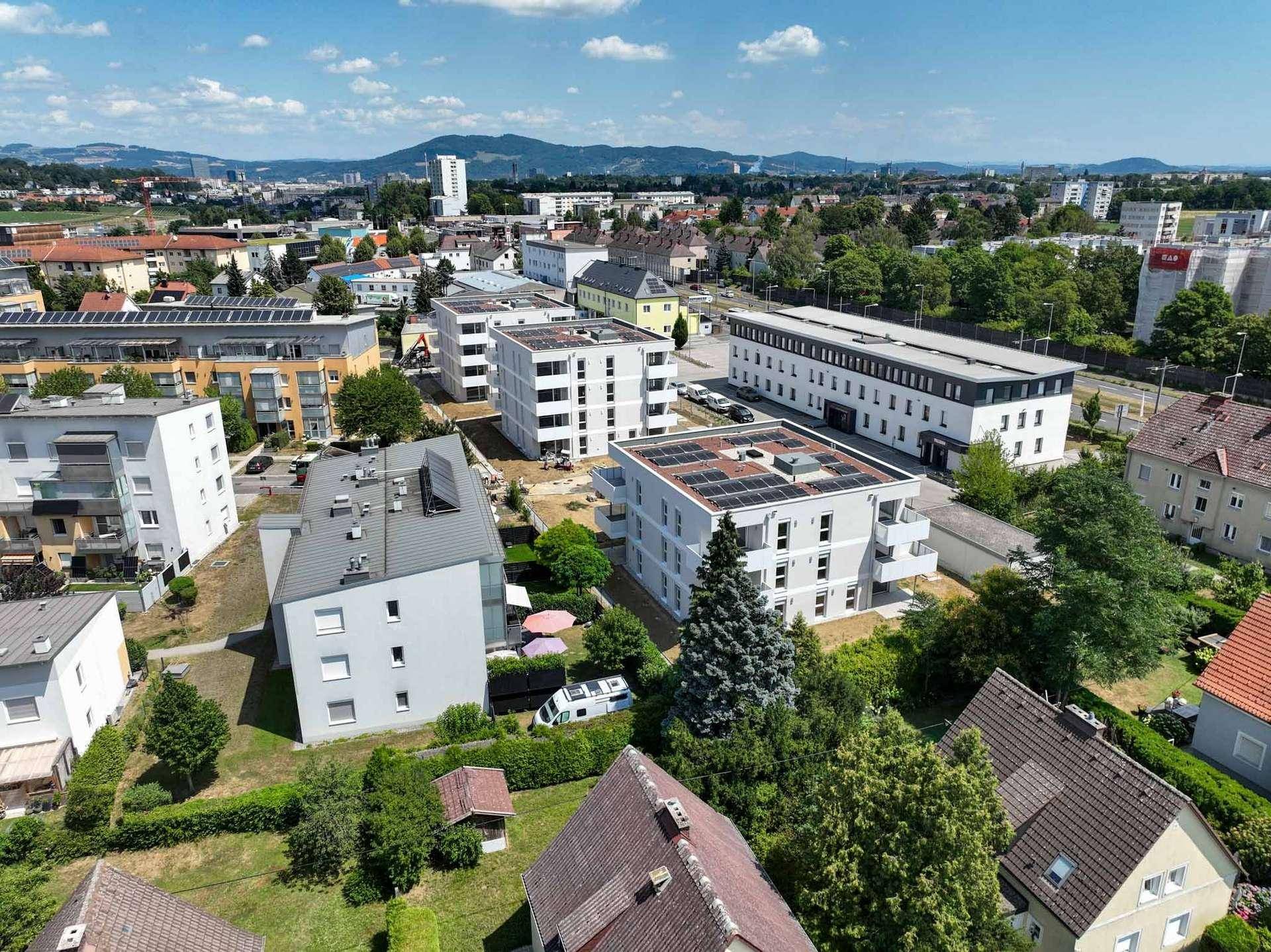 Weitläufige Luftaufnahme einer Wohnsiedlung mit neuen und bestehenden Gebäuden.