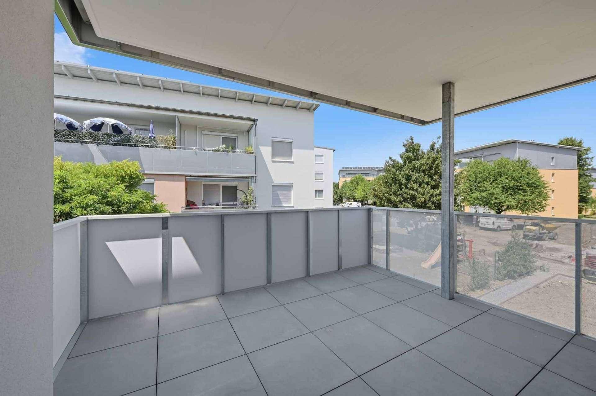 Geräumiger Balkon mit modernen Fliesen und Glasgeländer, bietet Blick auf die Umgebung.