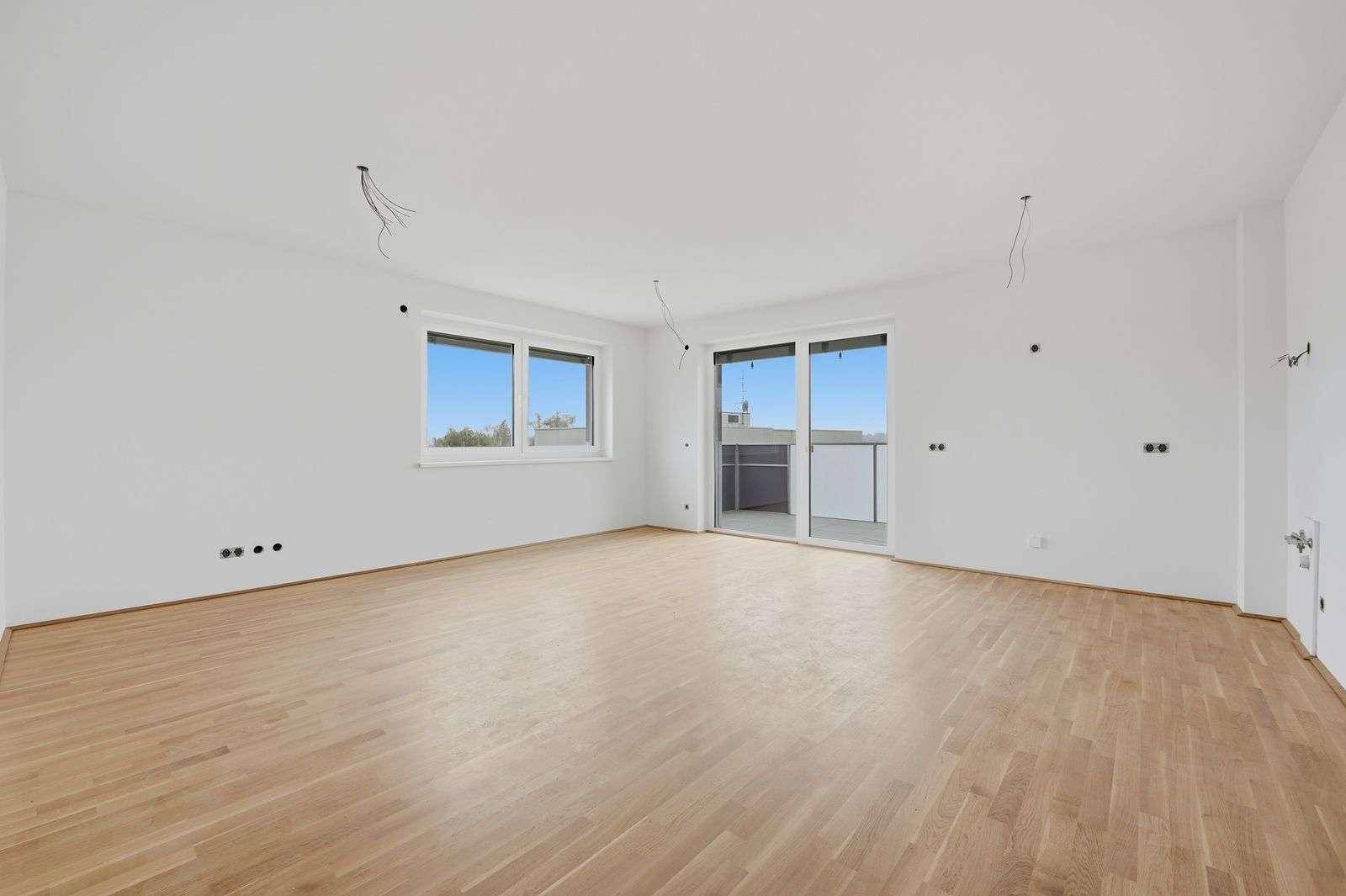 Heller, unmöblierter Raum mit Holzboden und Zugang zu einem Balkon, ideal für Wohn- oder Schlafzimmer.