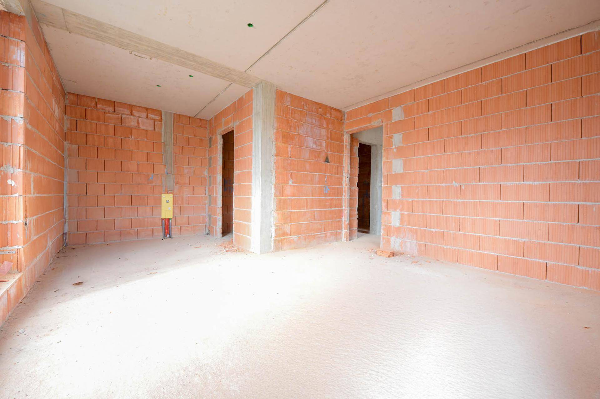 Rohbau-Innenraum mit Ziegelwänden und Türöffnungen, bereit für den weiteren Ausbau.