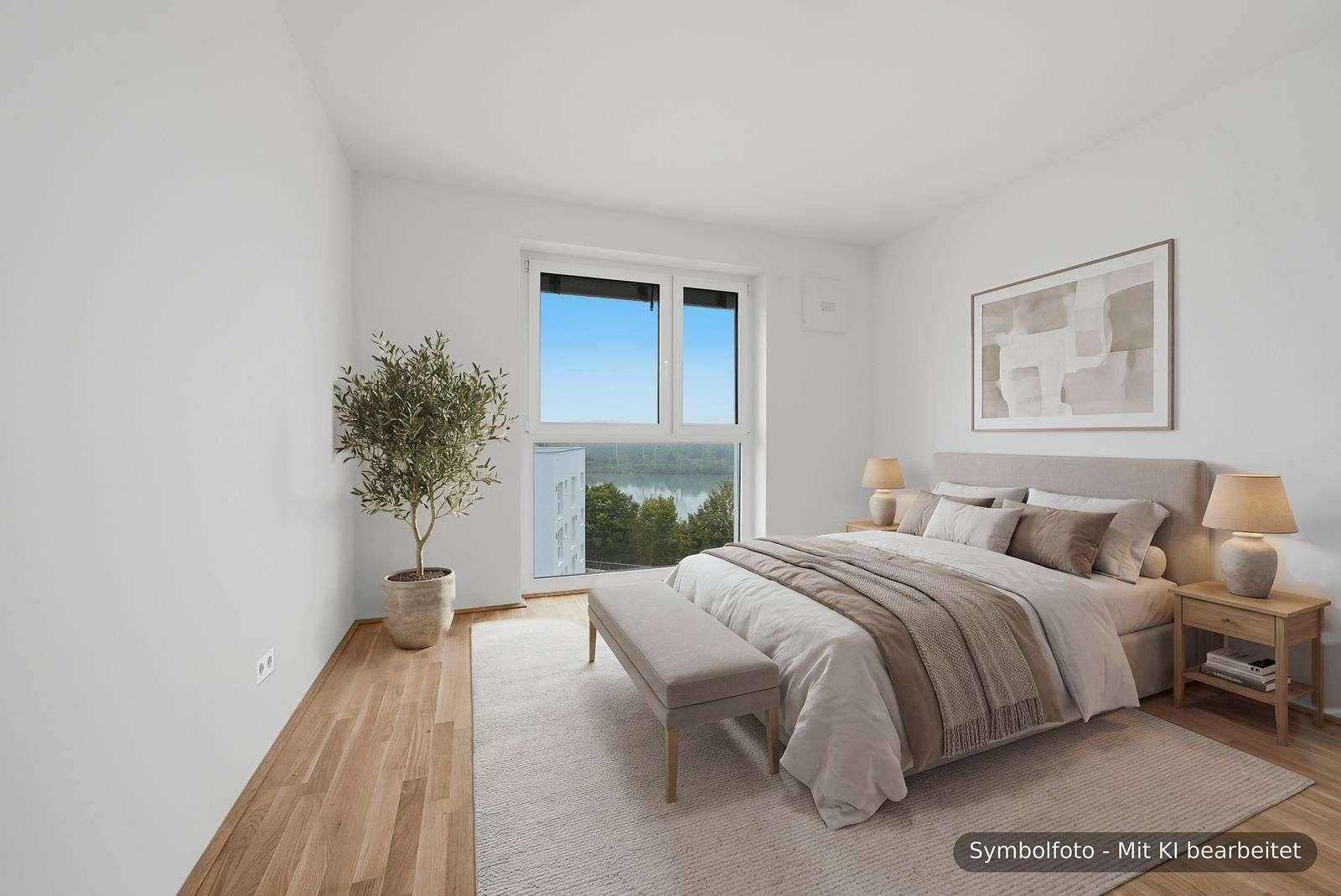 Helles Schlafzimmer mit Holzboden, modernem Bett und Fenster mit Seeblick.