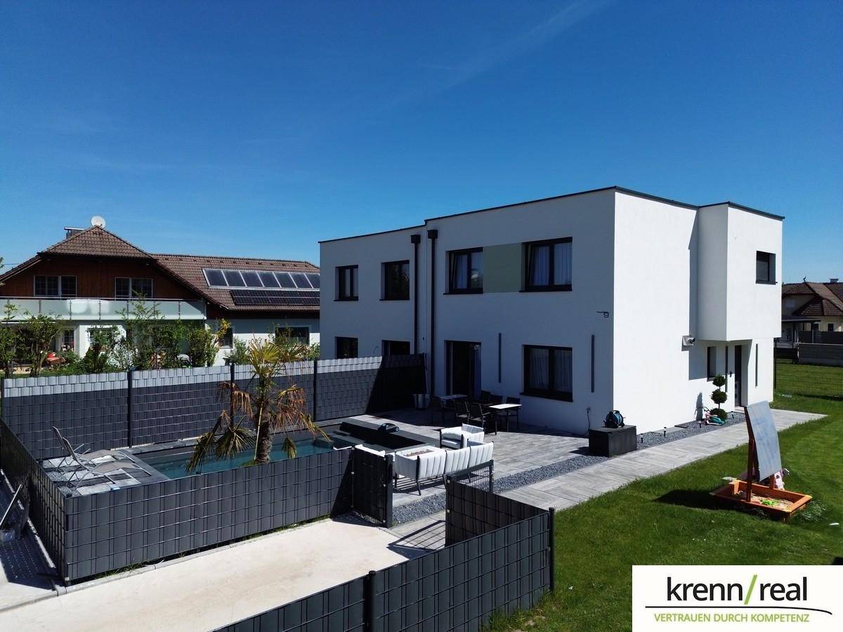 Ansicht des modernen Hauses von der Seite mit Poolbereich und gepflegtem Rasen.