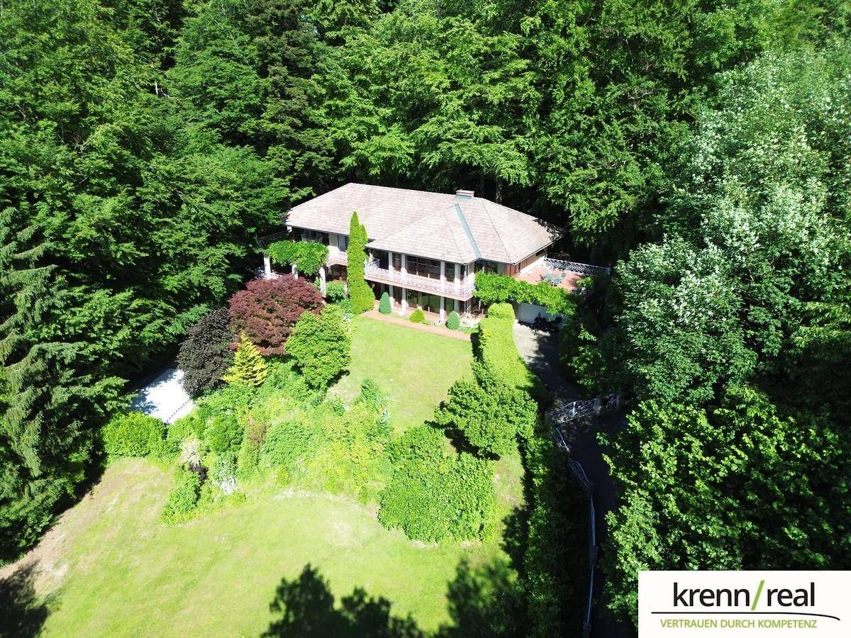 Luftaufnahme einer großzügigen Villa, idyllisch eingebettet in einen weitläufigen Wald mit großem Grundstück.