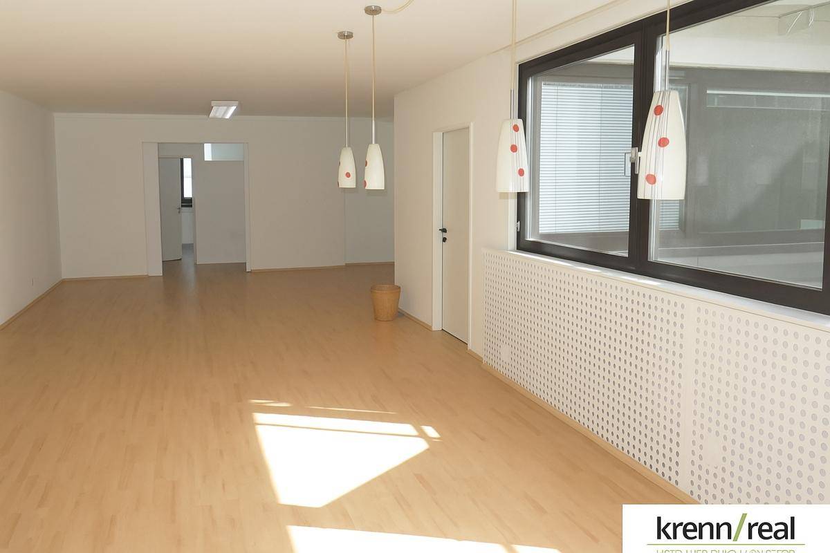 Geräumiges, helles Büro mit Laminatboden und modernen Hängelampen, bietet vielseitige Nutzungsmöglichkeiten.