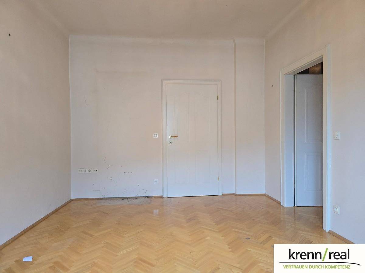 Leerer Raum mit Parkettboden und zwei weißen Türen.