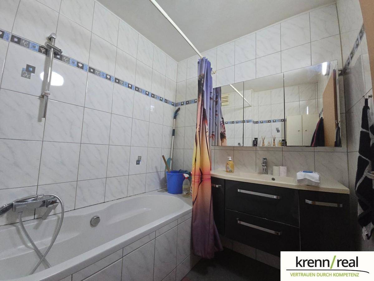 Gefliestes Badezimmer mit Badewanne, Waschtisch und Spiegelschrank.