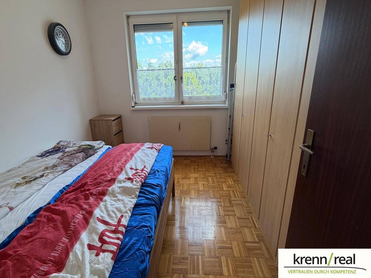 Schlafzimmer mit Einzelbett, großem Kleiderschrank und Fenster mit Blick ins Grüne.