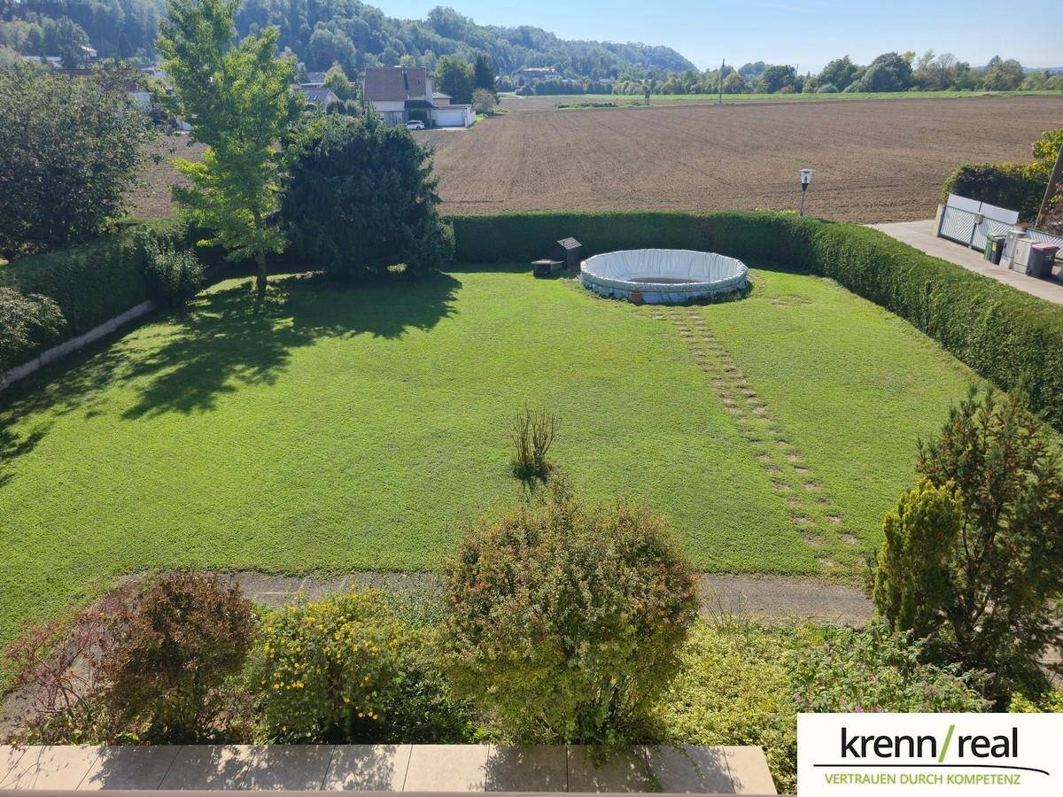 Großer Garten mit Rasenfläche, oberirdischem Pool und Blick auf die umliegende Landschaft und Felder.