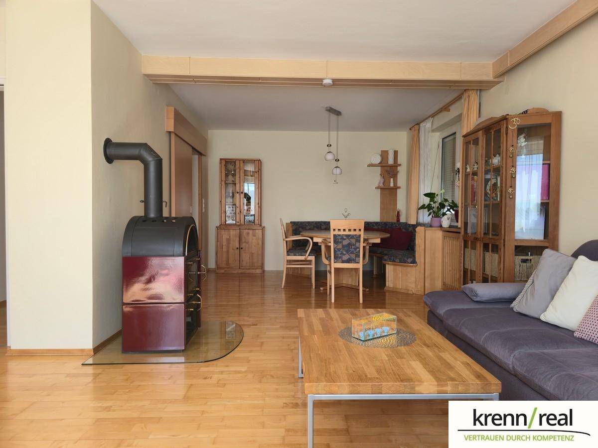 Gemütlicher Wohn-Essbereich mit Holzboden, Kaminofen und traditionellen Holzmöbeln für eine warme Atmosphäre.