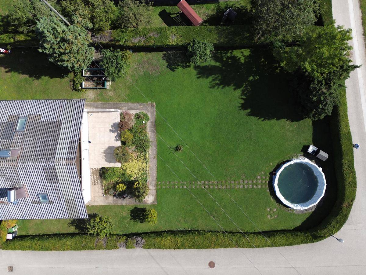 Luftaufnahme des Grundstücks mit Haus, Terrasse, Garten und oberirdischem Pool in sonniger Lage.