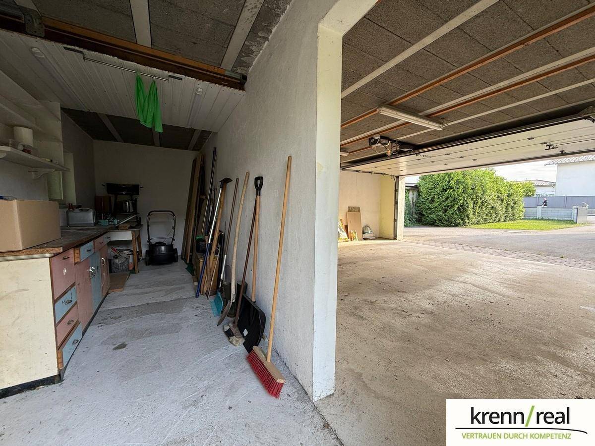 Geräumige Garage mit Betonboden, Stauraum und Blick ins Freie.