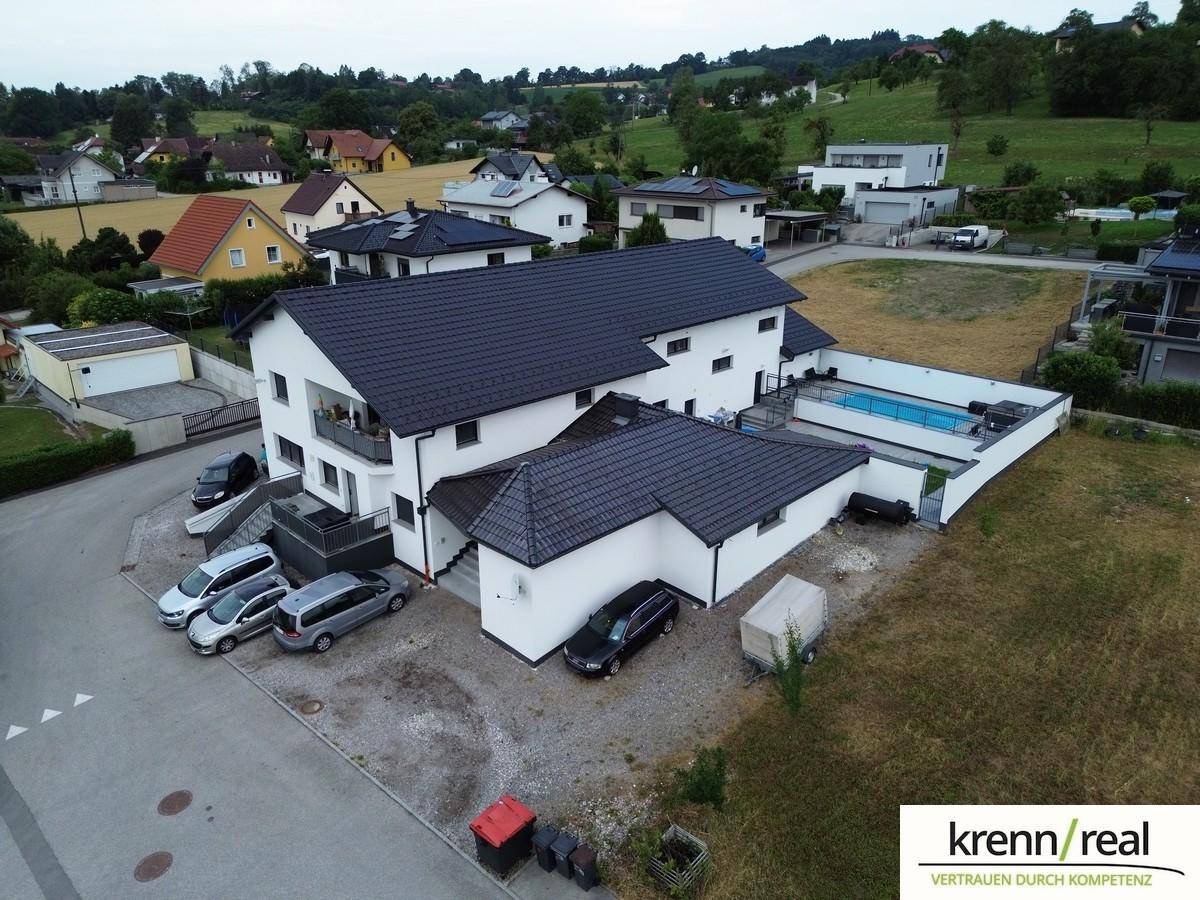 Moderne Wohnanlage mit Swimmingpool, mehreren Parkplätzen und Blick auf die Umgebung.