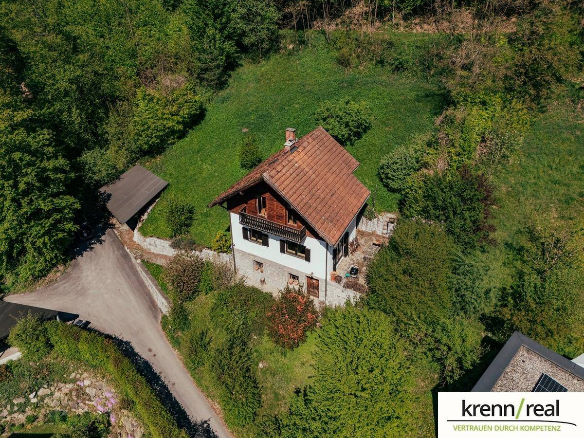 Luftaufnahme eines Hauses in ländlicher Umgebung, umgeben von Wald und Wiesen.