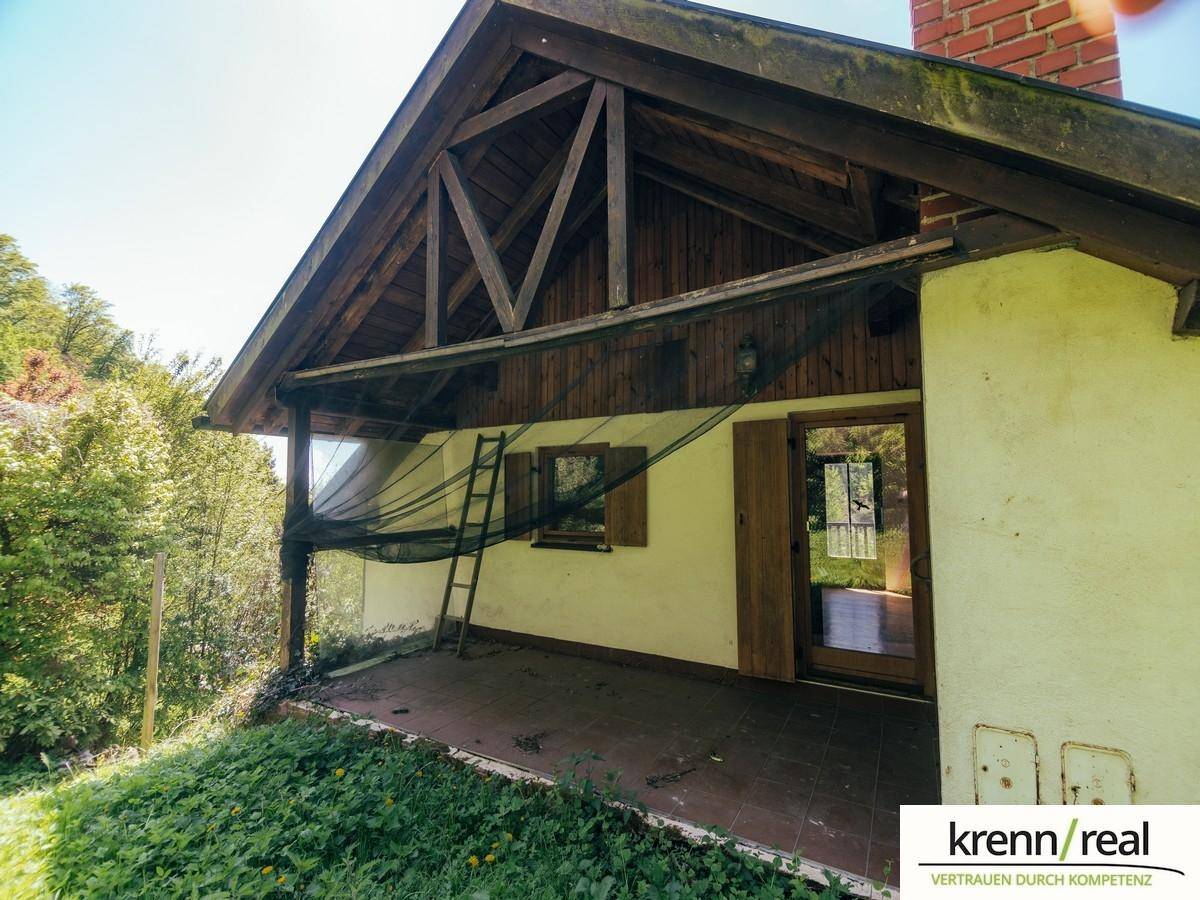 Überdachte Terrasse mit Fliesenboden und Blick ins Grüne, ideal für entspannte Stunden.