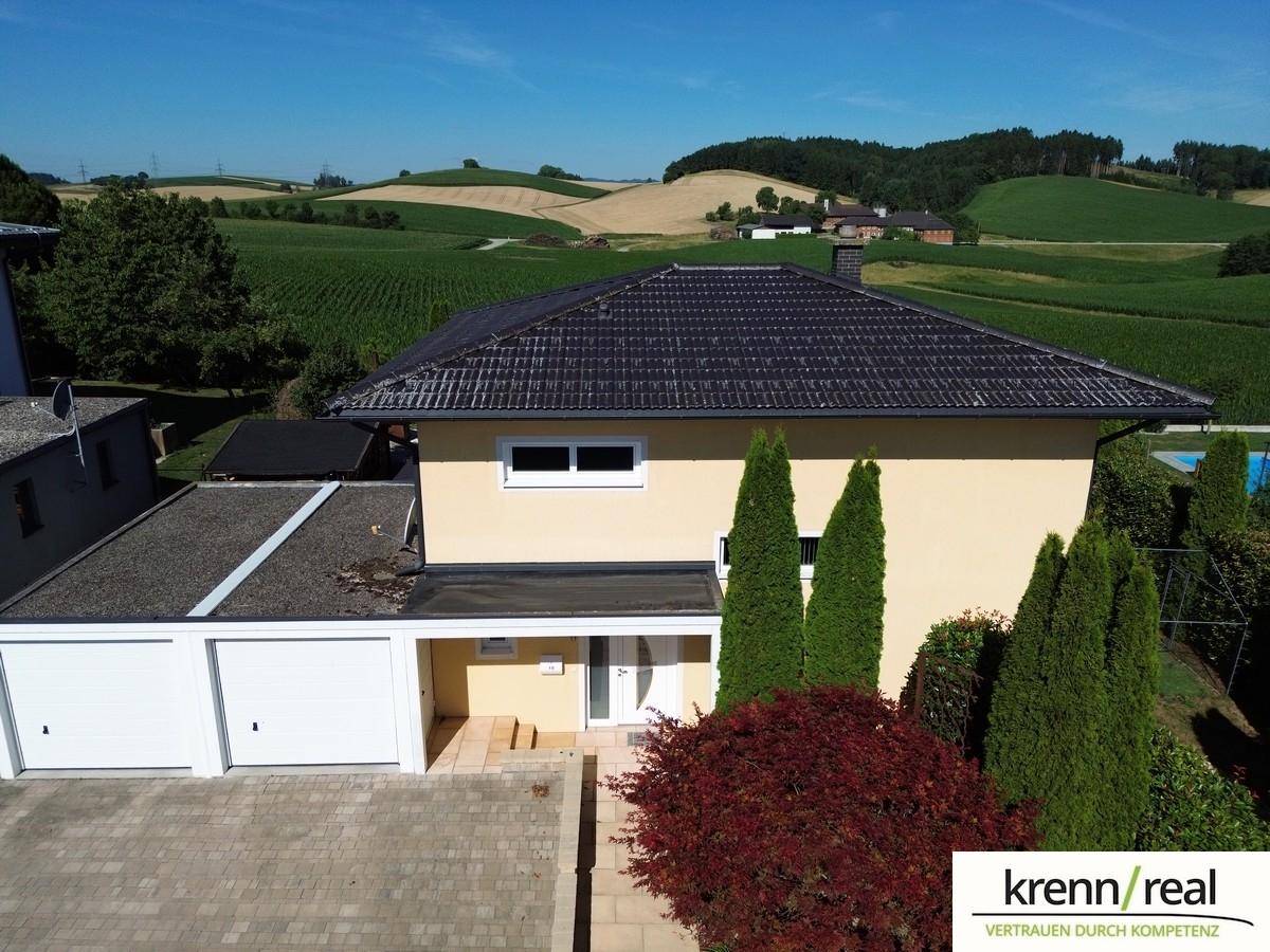 Seitenansicht des Hauses mit Doppelgarage und gepflasterter Einfahrt.