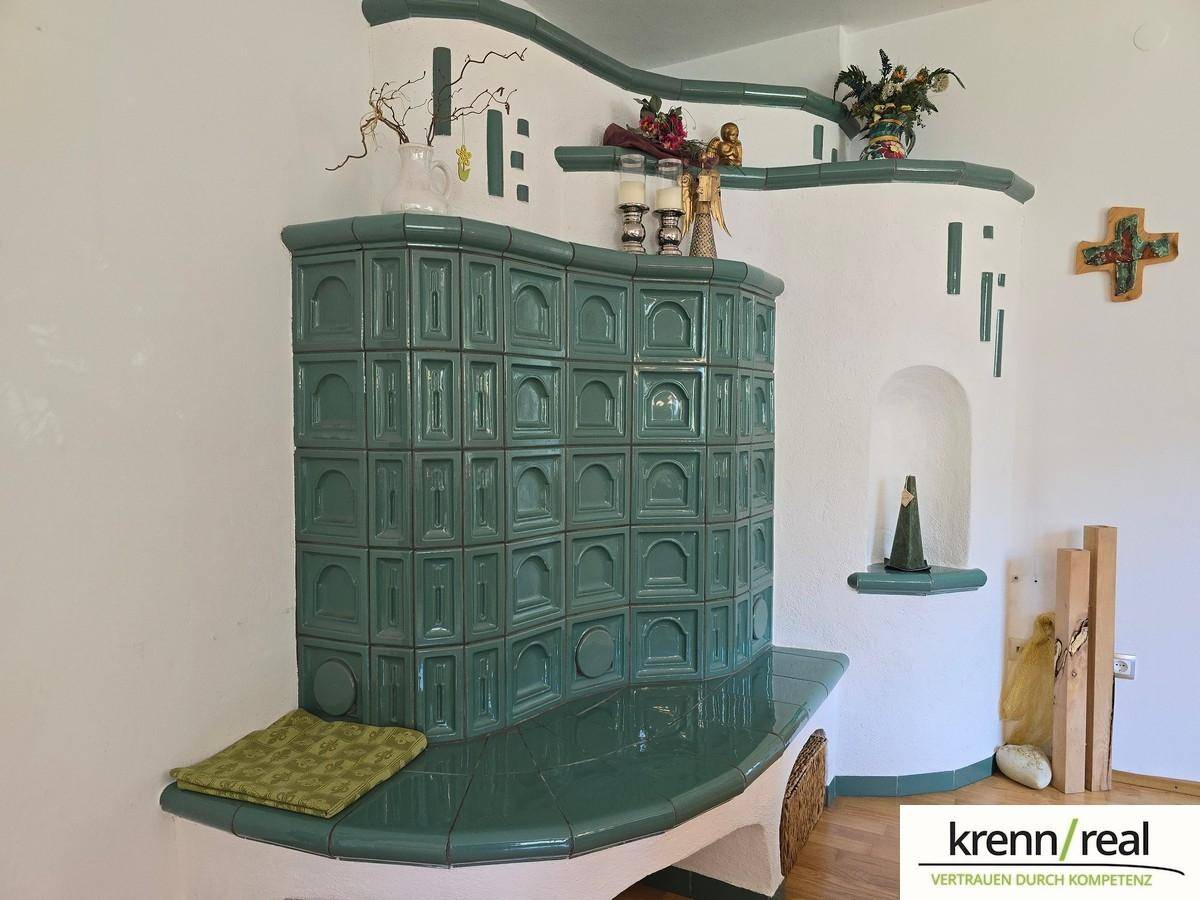 Traditioneller grüner Kachelofen als zentrales Heizelement und dekoratives Highlight im Raum.