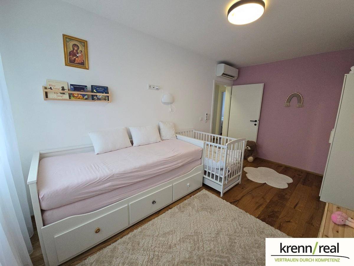 Kinderzimmer mit Einzelbett, Babybett und farbiger Wandgestaltung.