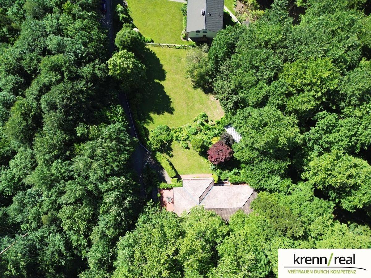 Blick von oben auf ein Anwesen mit großem Garten und angrenzendem Waldgebiet.
