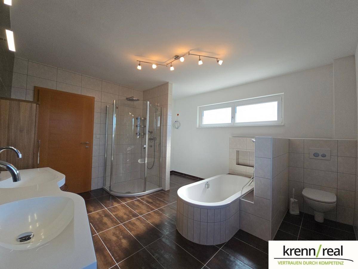 Modernes Badezimmer mit Badewanne, Dusche, Doppelwaschbecken und Fenster.