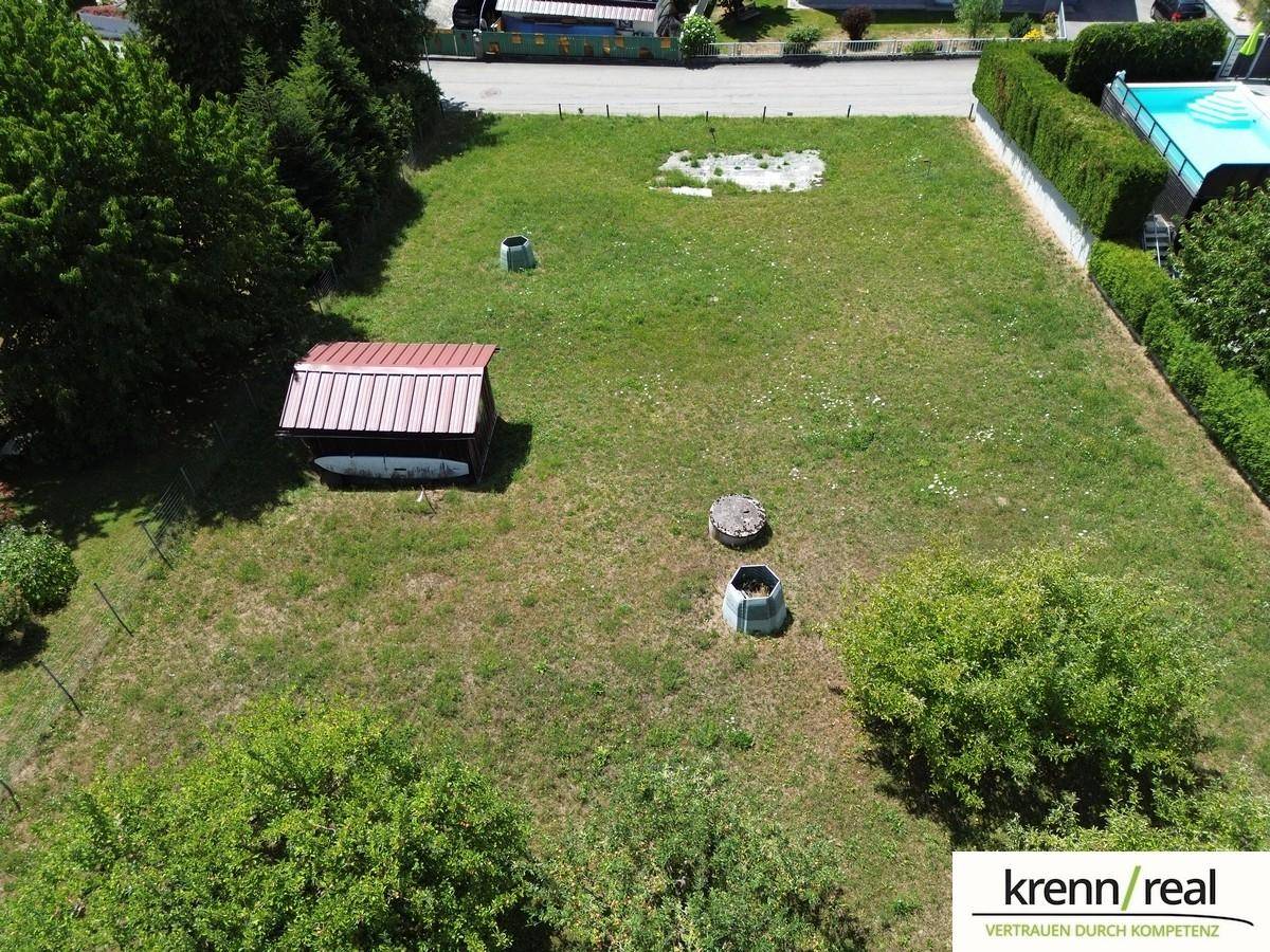 Grundstück mit Rasenfläche, Schuppen und Blick auf die Nachbarschaft mit einem Pool.