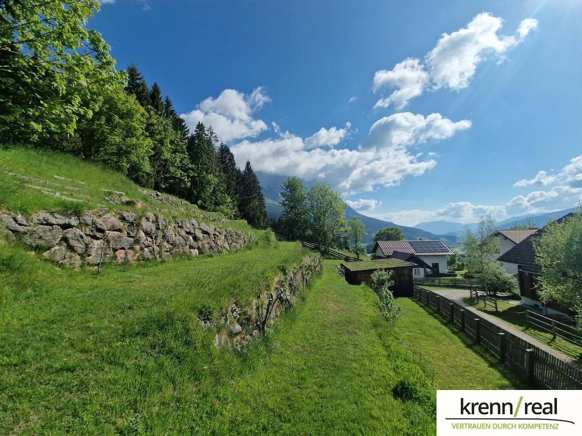 Gestufte Gartenanlage mit Natursteinmauern und grünen Rasenflächen am Hang.