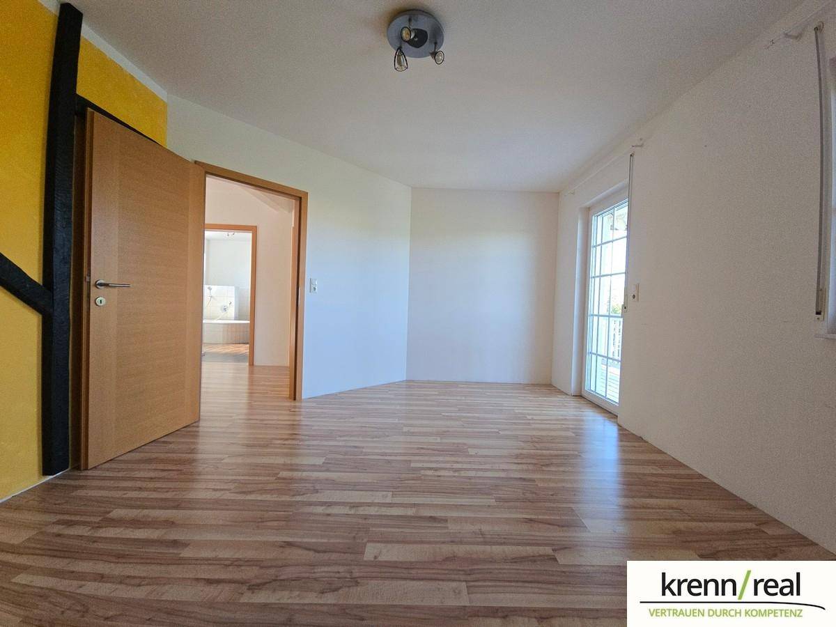 Heller, leerer Raum mit Laminatboden und Zugang zu einem Balkon oder Terrasse.
