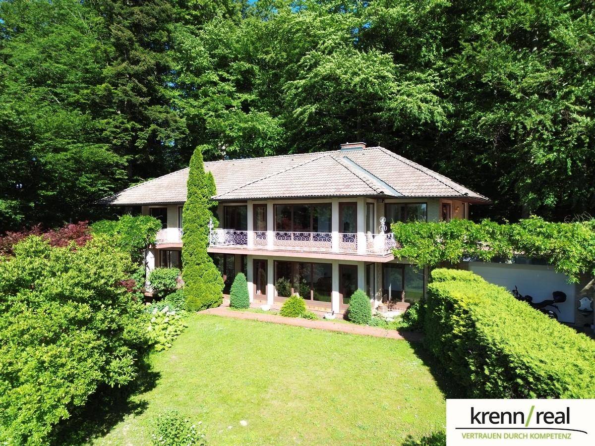 Geräumige Villa mit weitläufigem Rasen und dichtem Baumbestand, die eine ruhige Wohnlage bietet.