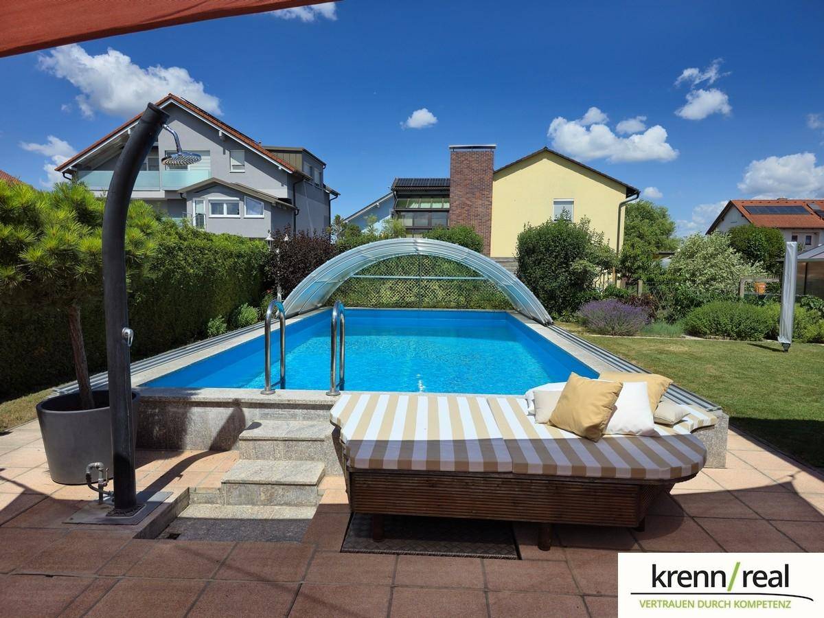 Gepflegter Poolbereich im Garten mit Liegefläche und sonniger Atmosphäre.