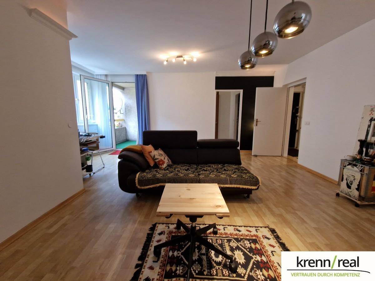 Geräumiges Wohnzimmer mit Parkettboden, bequemen Sofa und moderner Deckenbeleuchtung.