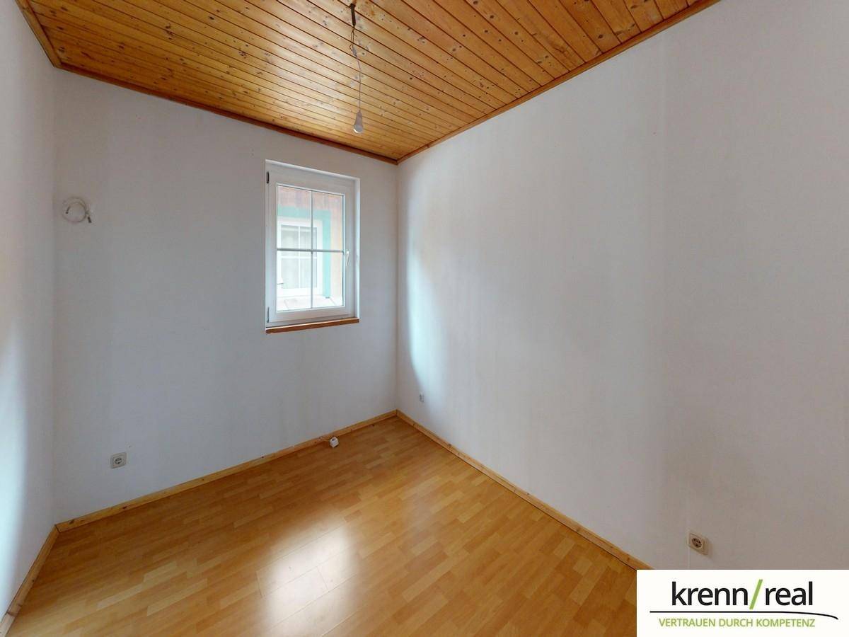 Helles Zimmer mit Holzbalkendecke, Parkettboden und weiß gestrichenen Wänden, in gutem Zustand.